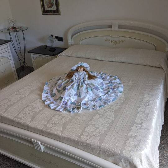 Bambola da letto modello "Ariel" adagiata sul letto matrimoniale. Vista obliqua.