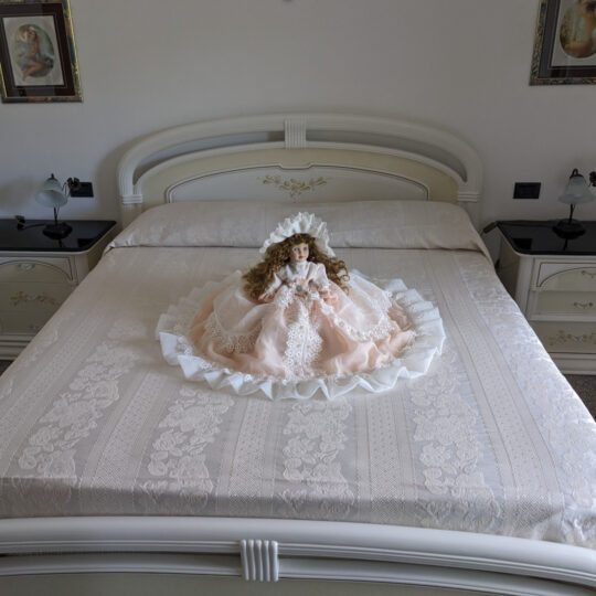 Bambola da letto modello "Beatrice" adagiata sul letto matrimoniale. Vista frontale.