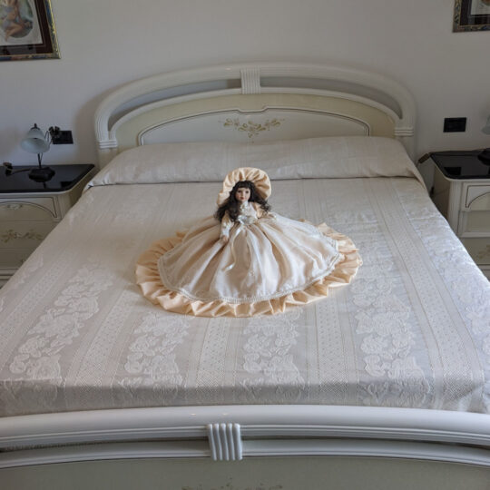 Bambola da letto modello "Emma" adagiata sul letto matrimoniale. Vista frontale.