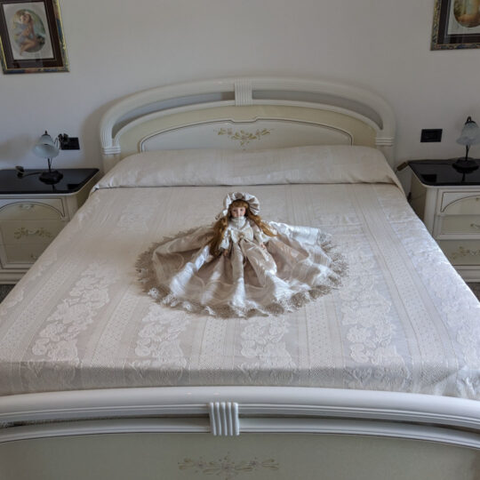 Bambola da letto modello "Eva" adagiata su letto matrimoniale. Vista frontale.