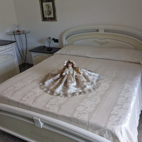 Bambola da letto modello "Eva" adagiata su letto matrimoniale. Vista obliqua.