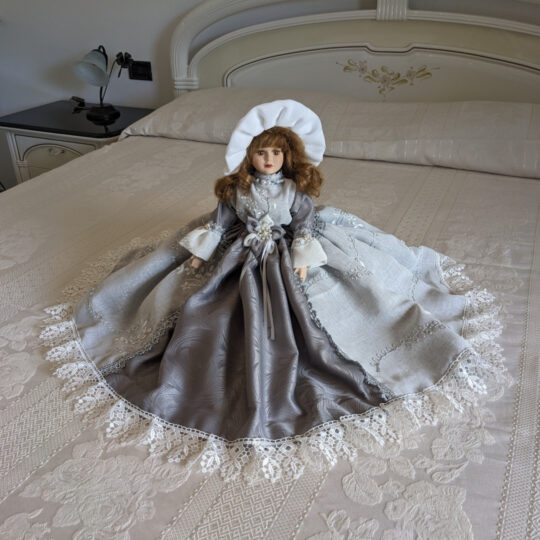 Bambola da letto modello "Gresy" adagiata su letto matrimoniale. Primo piano.