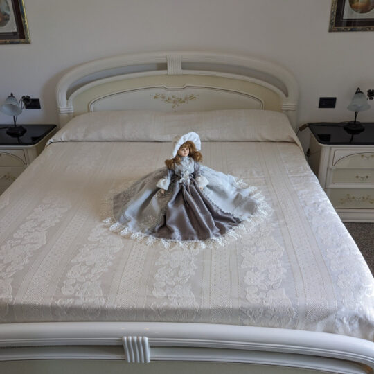 Bambola da letto modello "Gresy" adagiata su letto matrimoniale. Vista frontale.