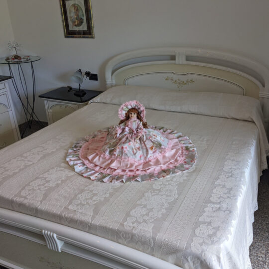 Bambola da letto modello "Roxana" adagiata su letto matrimoniale. Vista obliqua.