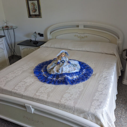 Bambola da letto modello "Stella" adagiata su letto matrimoniale. Vista obliqua.