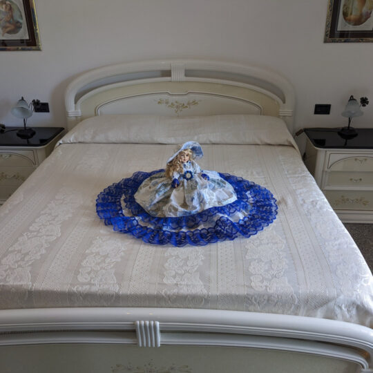 Bambola da letto modello "Stella" adagiata su letto matrimoniale. Vista frontale.